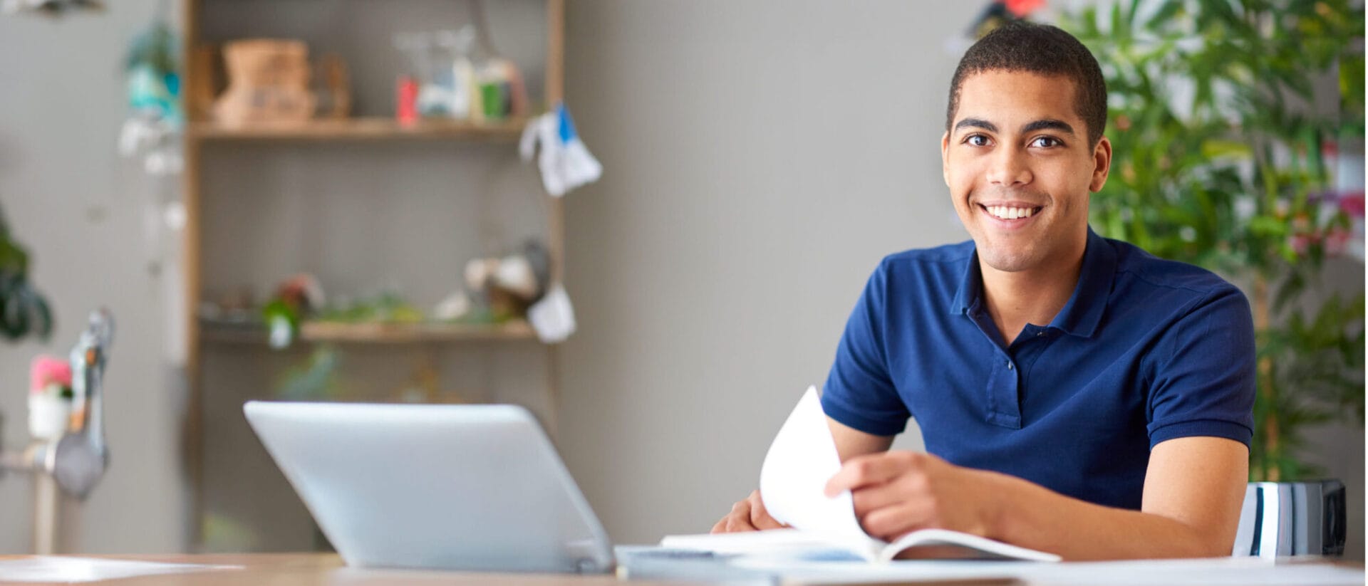 Smiling man sitting at desk with laptop.